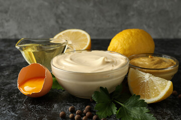 Bowl with mayonnaise and ingredients for cooking on black smokey background