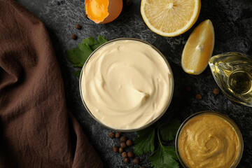 Bowl with mayonnaise and ingredients for cooking on black smokey background