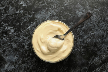 Bowl with mayonnaise and spoon on black smokey background