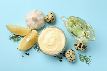 Bowl with mayonnaise and ingredients on blue background