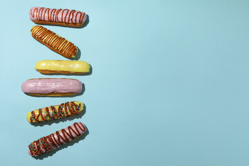 Tasty eclairs with different topping on blue background