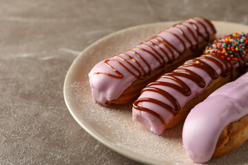 Plate with eclairs with custard on gray background