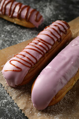 Baking paper with tasty eclairs on black smokey background
