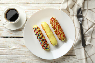 Concept of sweet meal with plate of delicious eclairs on wooden background