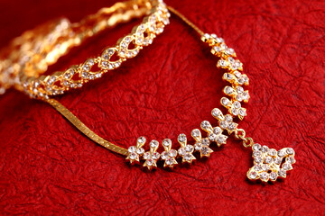 Gold Necklaces on red textured cloth background.