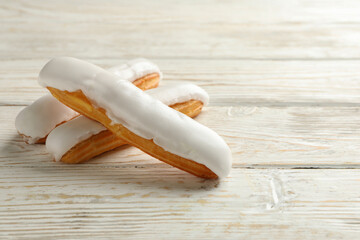 Tasty eclairs with custard on wooden background