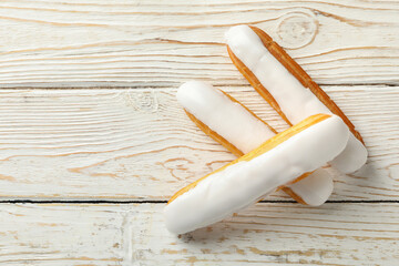 Tasty eclairs with custard on wooden background