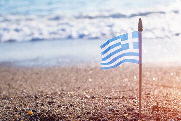 Small Greek waving flag flying over sea water waves. Travel to Greece or national Day. Copy space