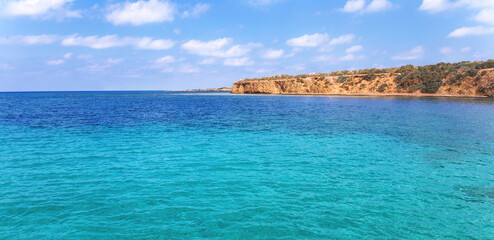 Fototapeta na wymiar View of rocky coast turquoise sea waters on a sunny day with blue sky. Blue lagoon. Destination scenic seascape. Travel and adventure. Cyprus. Mediterranean. No people. Vivid web banner