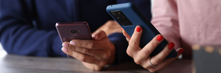 Two women are holding smartphones in their hands. Smartphone remote applications concept
