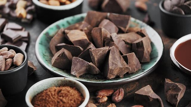 Organic chocolate chunks, melted chocolate in a bowl and ingredients for chocolate, rotation around an axis. Confectionery home concept