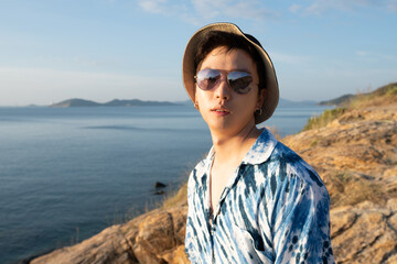 Fashion young man Wear a fashionable sunglasses and hat on seacoast , asian male at seaside.