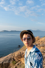 Fototapeta na wymiar Fashion young man Wear a fashionable sunglasses and hat on seacoast , asian male at seaside.