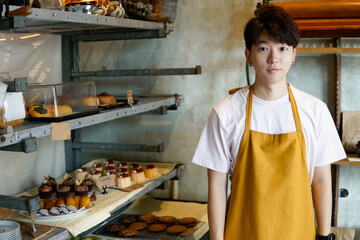 Portrait of handsome baker at the bakery background - Asian Man wearing an apron in bakery house