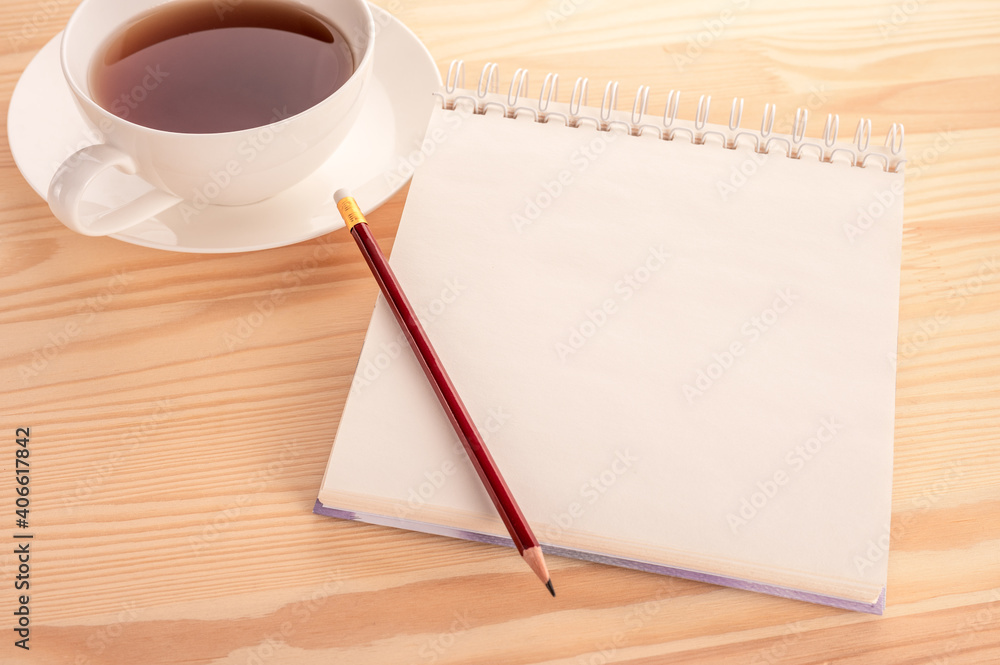 Poster mockup notebook with a blank page on a wooden table and a cup of tea. open blank page notebook with 