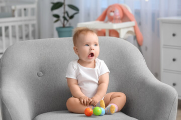 Cute little baby sitting in armchair at home