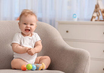 Cute little baby sitting in armchair at home