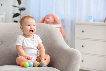 Cute little baby sitting in armchair at home