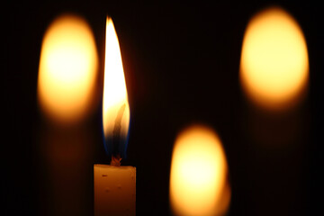 Closeup of burning candles on dark background.