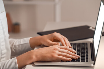 Woman working on laptop in evening, closeup