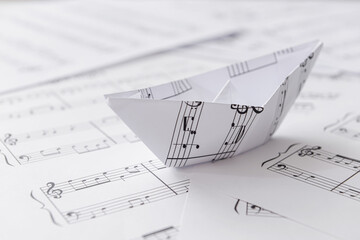 Paper boat with notes on music sheets