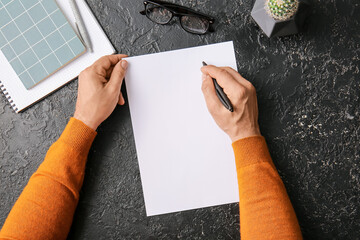 Male hands with blank paper sheet, glasses and notebooks on dark background