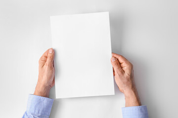 Male hands with blank paper sheet on light background