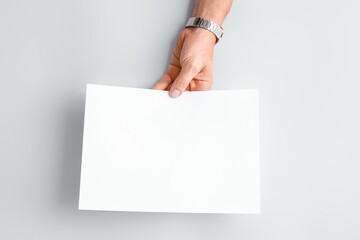 Male hand with blank paper sheet on light background