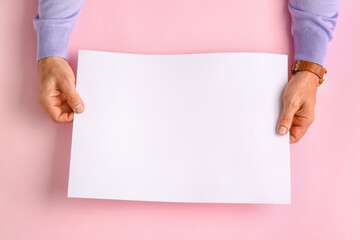 Male hands with blank paper sheet on color background