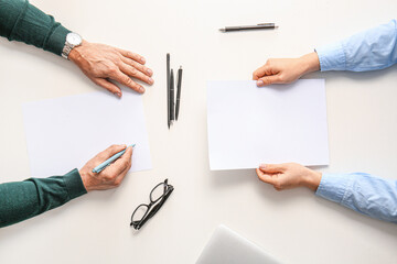 Hands with blank paper sheets on light background