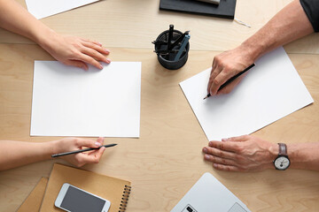 Hands with blank paper sheets on table