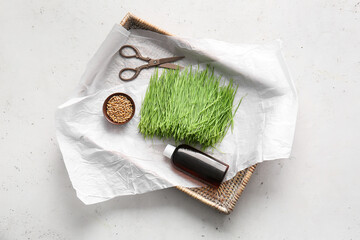 Fresh wheatgrass, seeds in bowl and bottle on light background