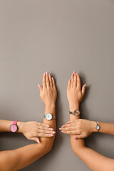 Female hands with stylish watches on grey background