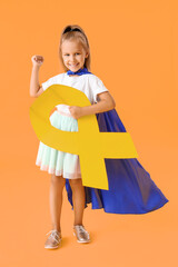 Little girl wearing superhero costume and with golden ribbon on color background. Childhood cancer...