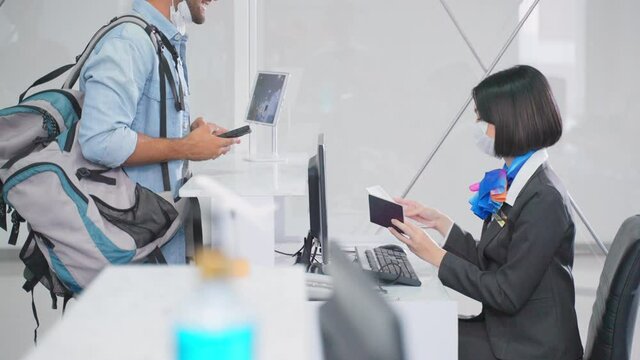Caucasian airline staff handing passport to passenger at the counter.