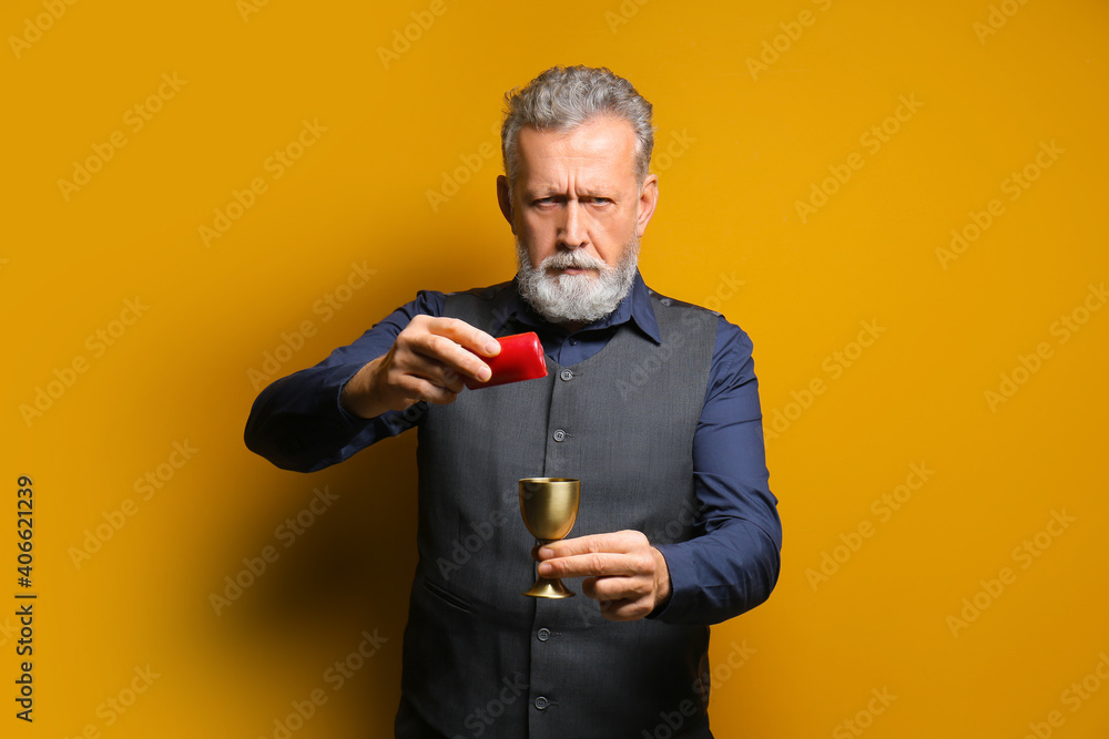 Wall mural Male fortune teller with candle and cup on color background