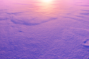beautiful blue and purple colored snow field surface illuminated by evening sunset , violet snow texture , original winter background