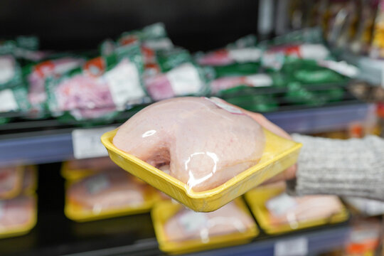 Image of packaged hen meat with woman hand in the supermarket
