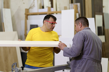 Two carpenters work with wood in the workshop