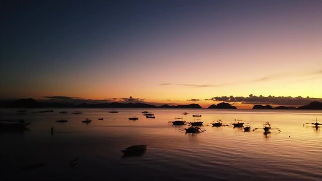 Low tracking shot over water and boats at sunset in El Nido, Palawan, Philippines