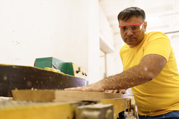 Male carpenter using saw for cutting wood at workshop