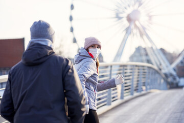 Fototapeta na wymiar Adult couple jogging in the city in masks during lockdown