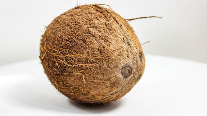 One whole coconut on a white wooden background.