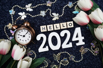 Hello 2024 alphabet letter decorate with alarm clock on blue knitted fabric background.