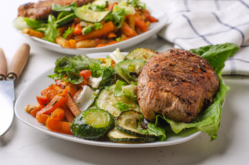 Plate of grilled chicken with vegetables on light background