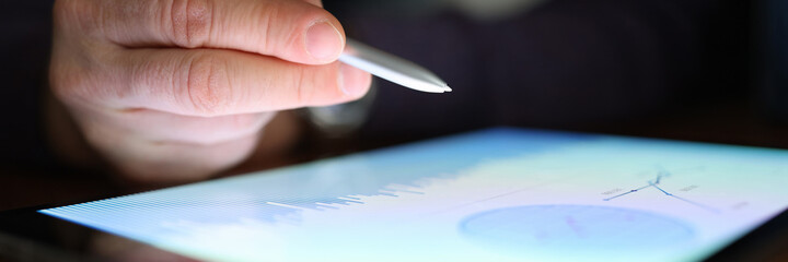 Male hand holds stylus over tablet with commercial indicators. Irregular Schedule in Online...