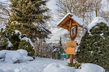 beautiful wooden signpost in winter garden covered with fresh snow