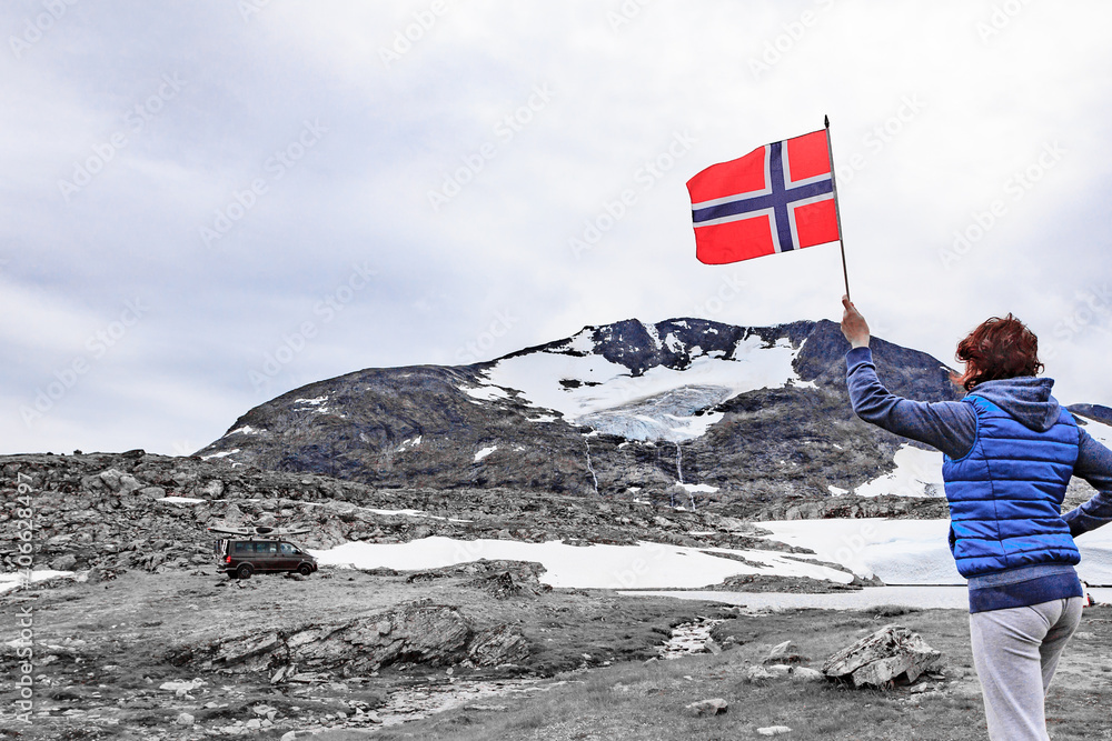 Sticker Woman holds norwegian flag in mountains Norway