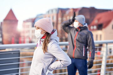 Adult couple jogging in the city in masks during lockdown