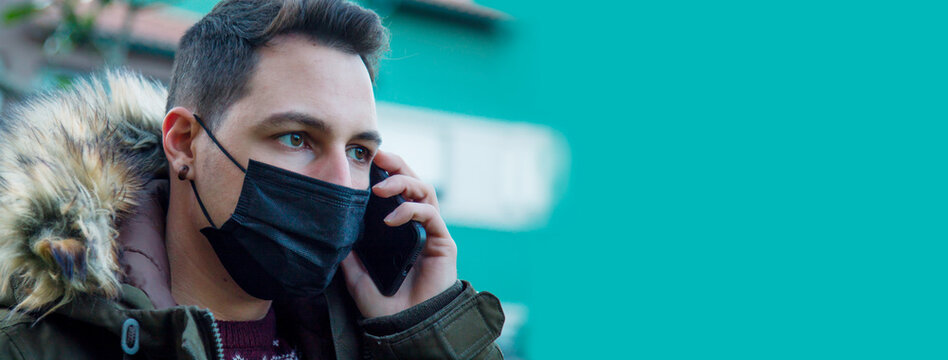 Man wears mask to prevent virus and for protection while using mobile phone. - Powered by Adobe